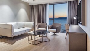 Una habitación de hotel moderna con sofá, sillones, una mesita de centro y televisión.