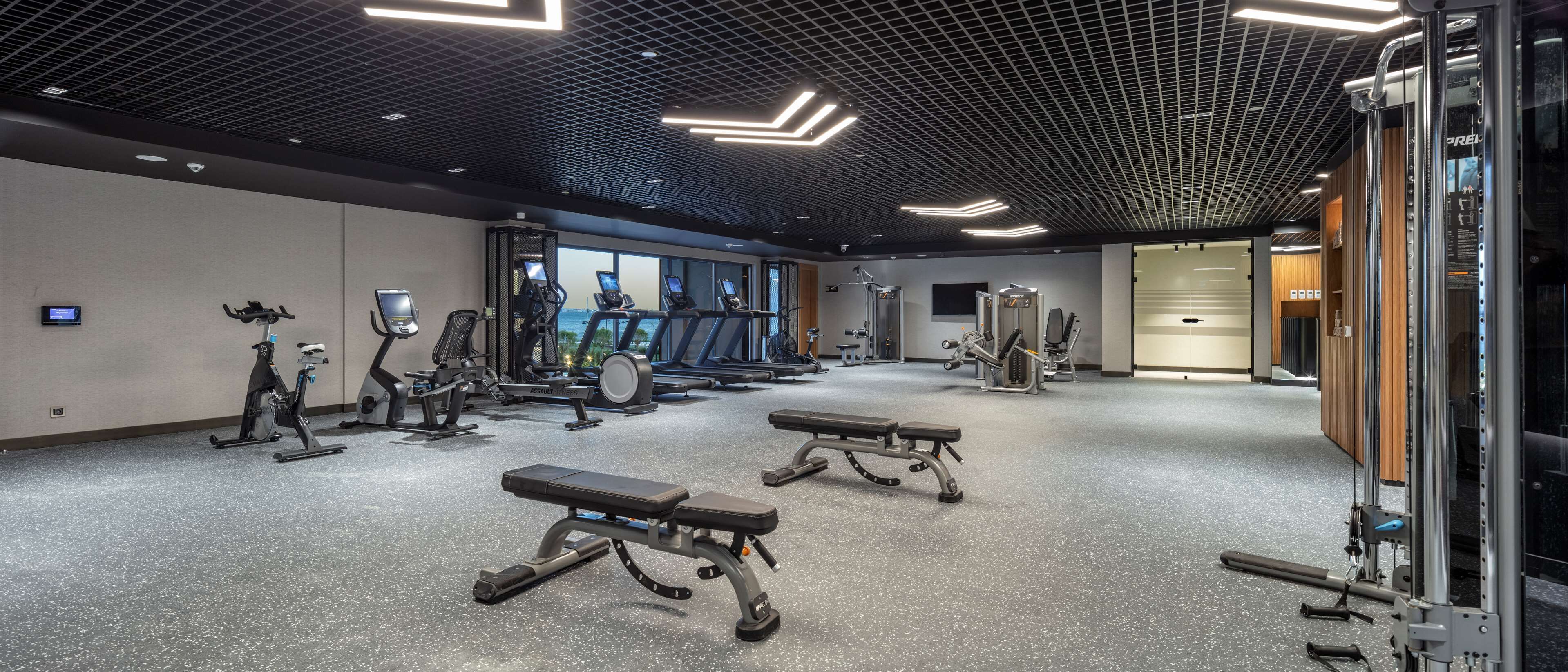 Una palestra con tapis roulant, ellittiche e panche per pesi.