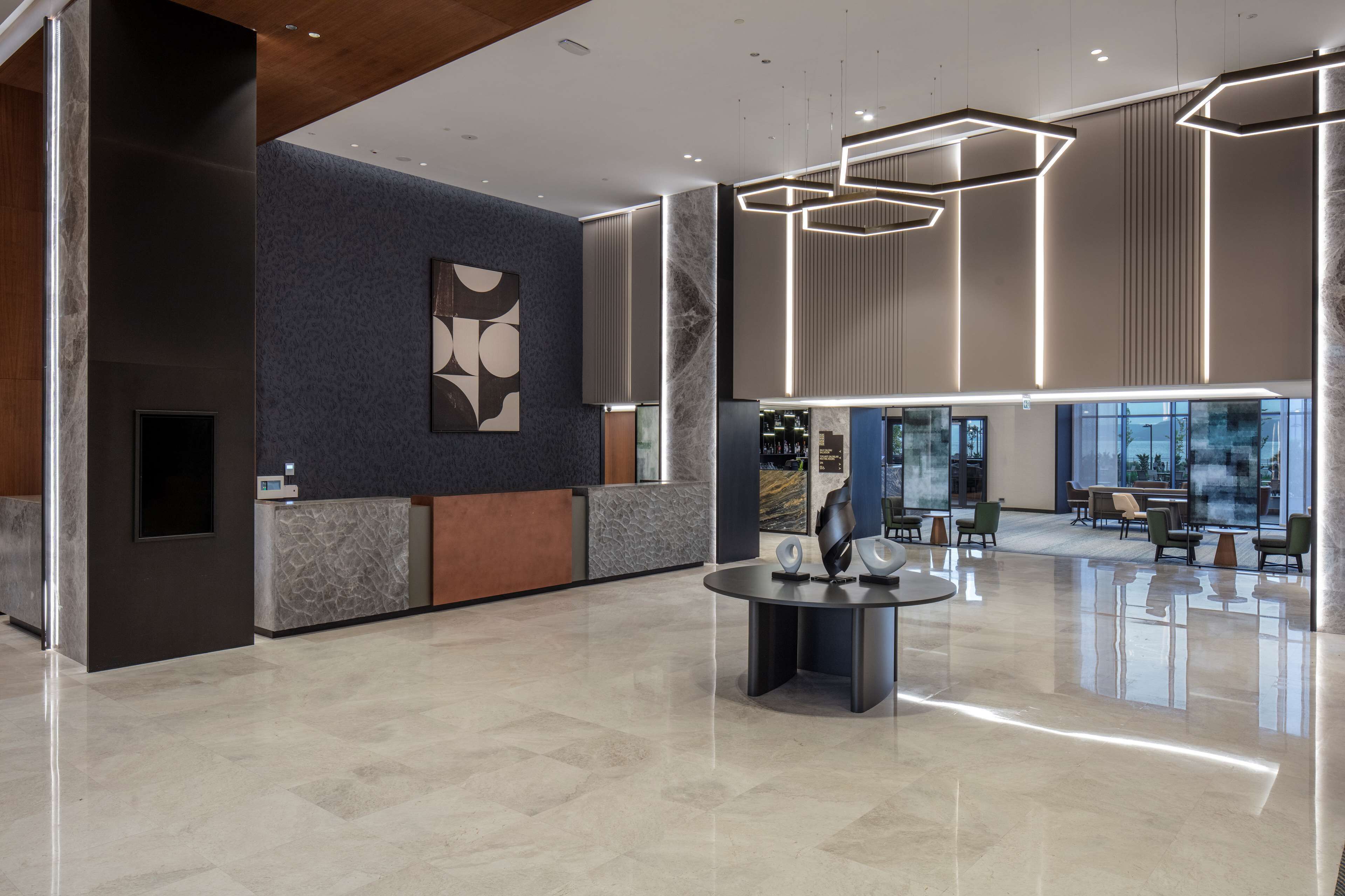 A modern lobby with a reception desk, a marble floor, and contemporary lighting fixtures.