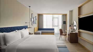 Een hotelkamer met een groot bed, een bureau, een stoel, een televisie en een raam met gordijnen.