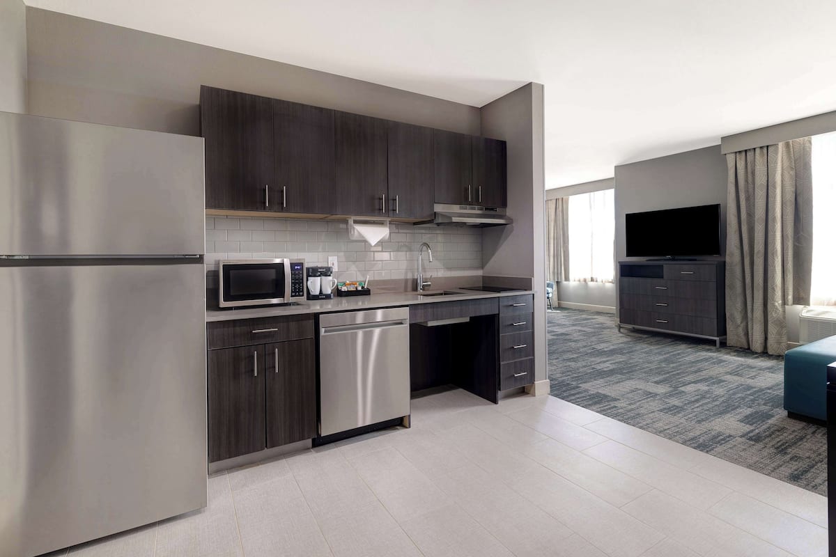 A modern kitchen with dark wood cabinets, stainless steel appliances, and a grey tiled backsplash.
