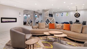 A modern lounge area with a curved sectional sofa, round coffee tables, and a patterned rug. - Homewood Suites by Hilton Oklahoma City Quail Springs (Oklahoma City)