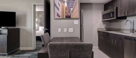 A modern kitchen with dark wood cabinets, a stainless steel microwave, and a built-in dishwasher.