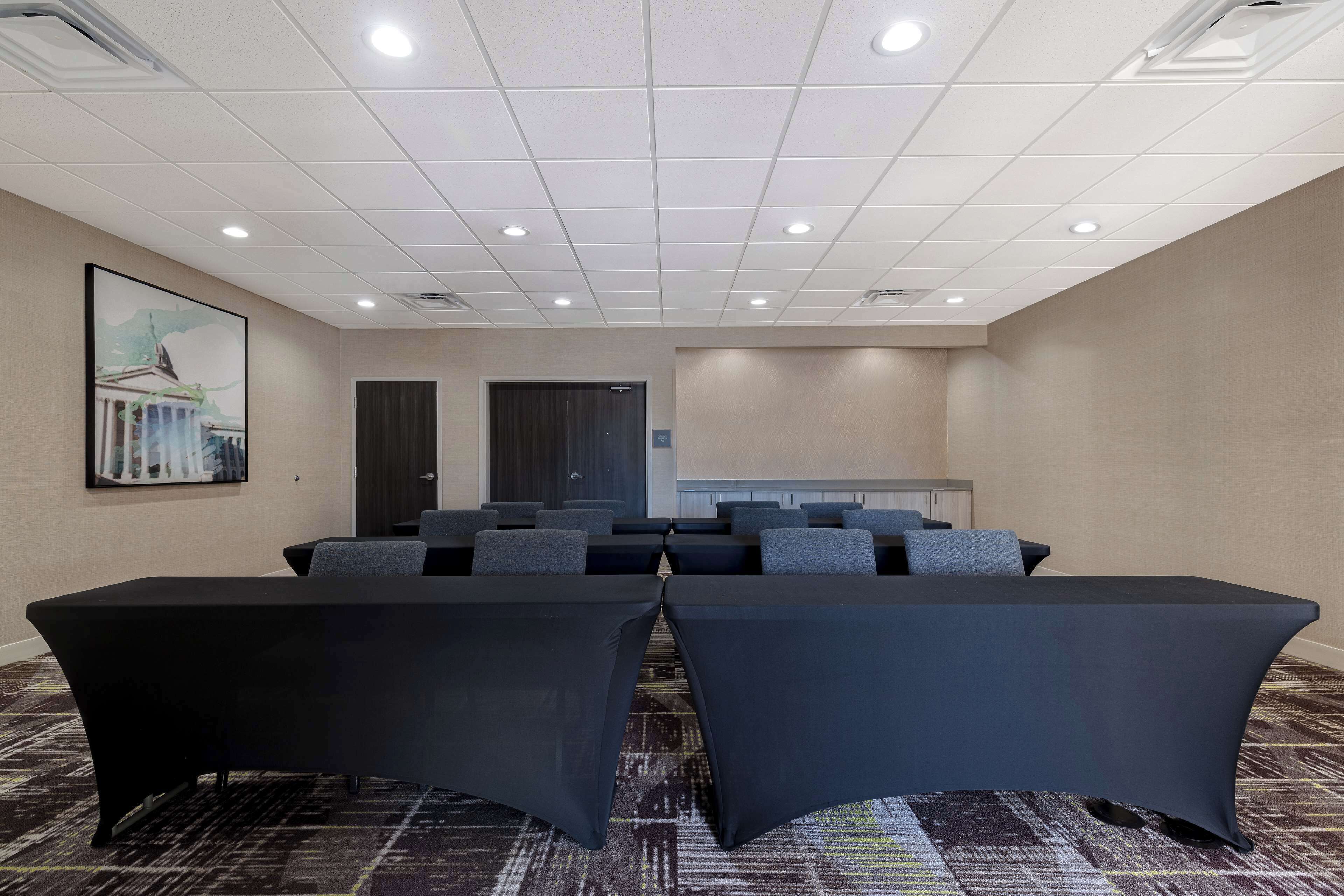 A conference room with a long table, multiple chairs, and a carpeted floor.