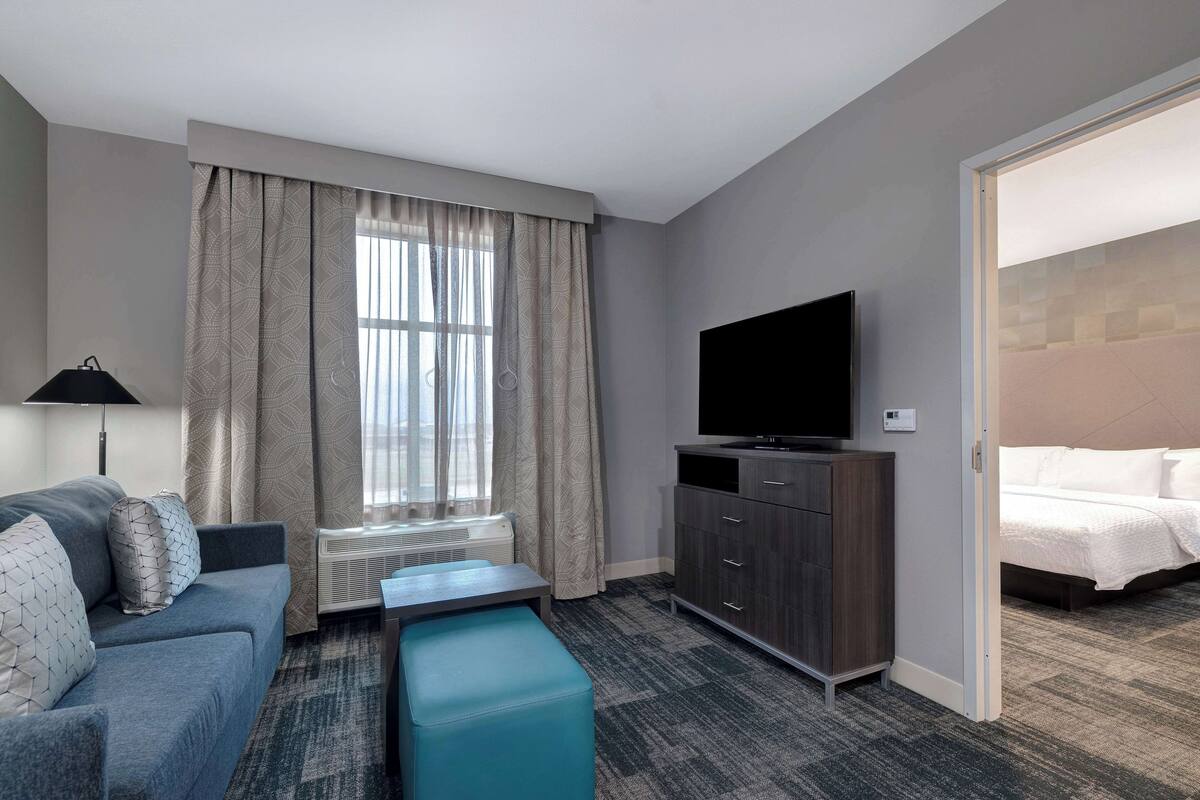 A hotel room with a sofa, a TV, a small table, a cabinet, and a bed.