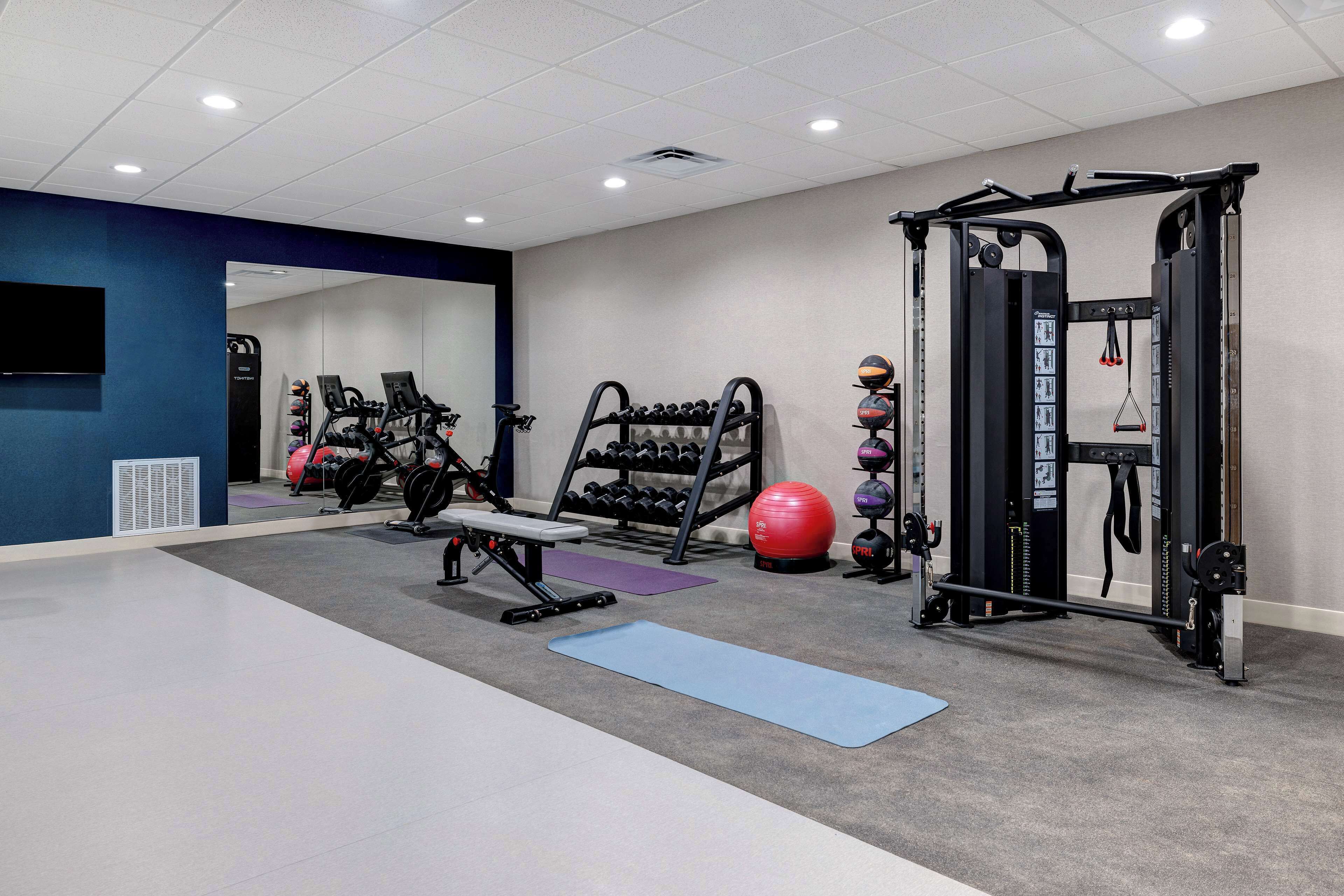 A gym with exercise equipment, a bench, and mats.