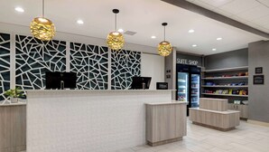 A hotel reception area with a modern design, including a reception desk, a minibar, and a 'Suite Shop' sign. - Homewood Suites by Hilton Oklahoma City Quail Springs (Oklahoma City)