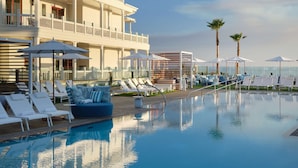 A pool area with lounge chairs and umbrellas, a building with balconies, and palm trees. - Shore House at The Del, LXR Hotels & Resorts (Coronado)