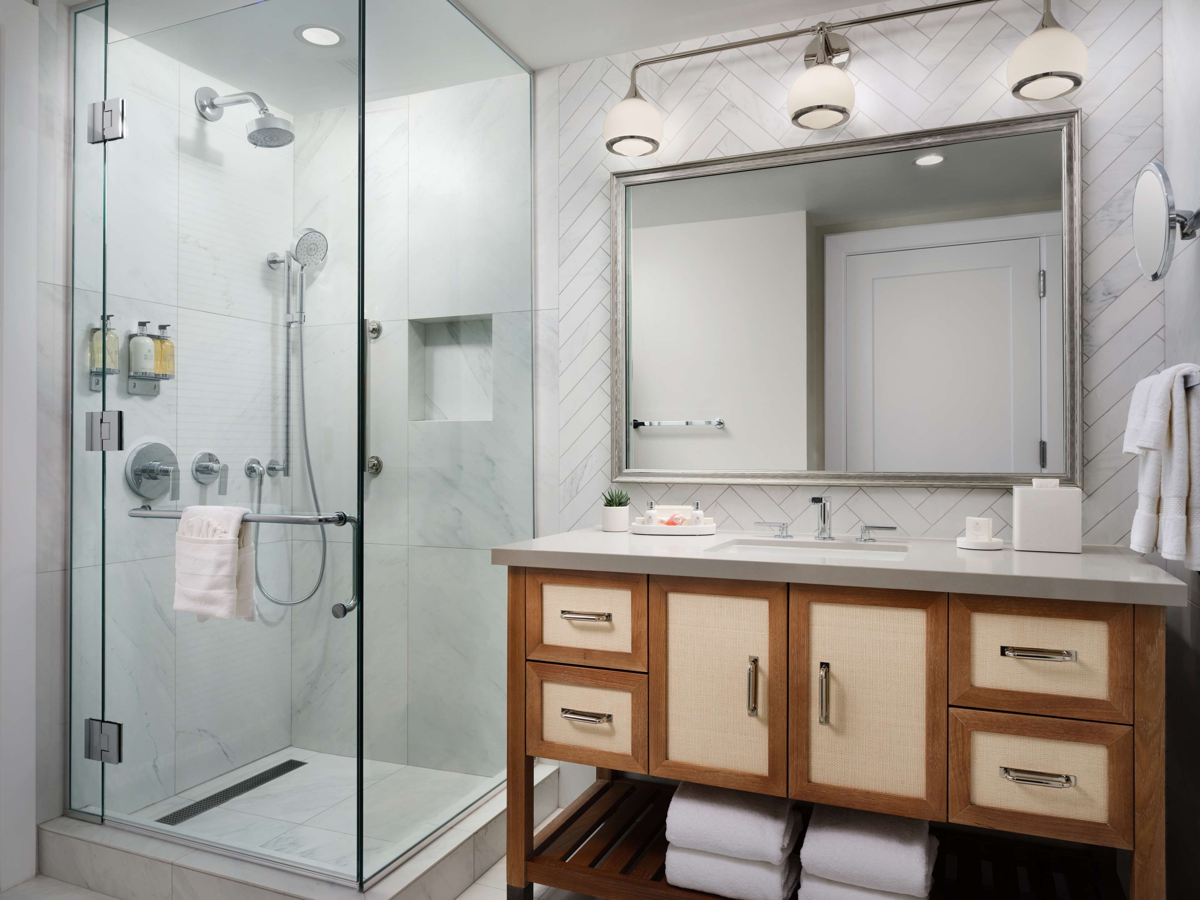 Un bagno moderno con doccia vetrata, un ampio specchio e mobili in legno.