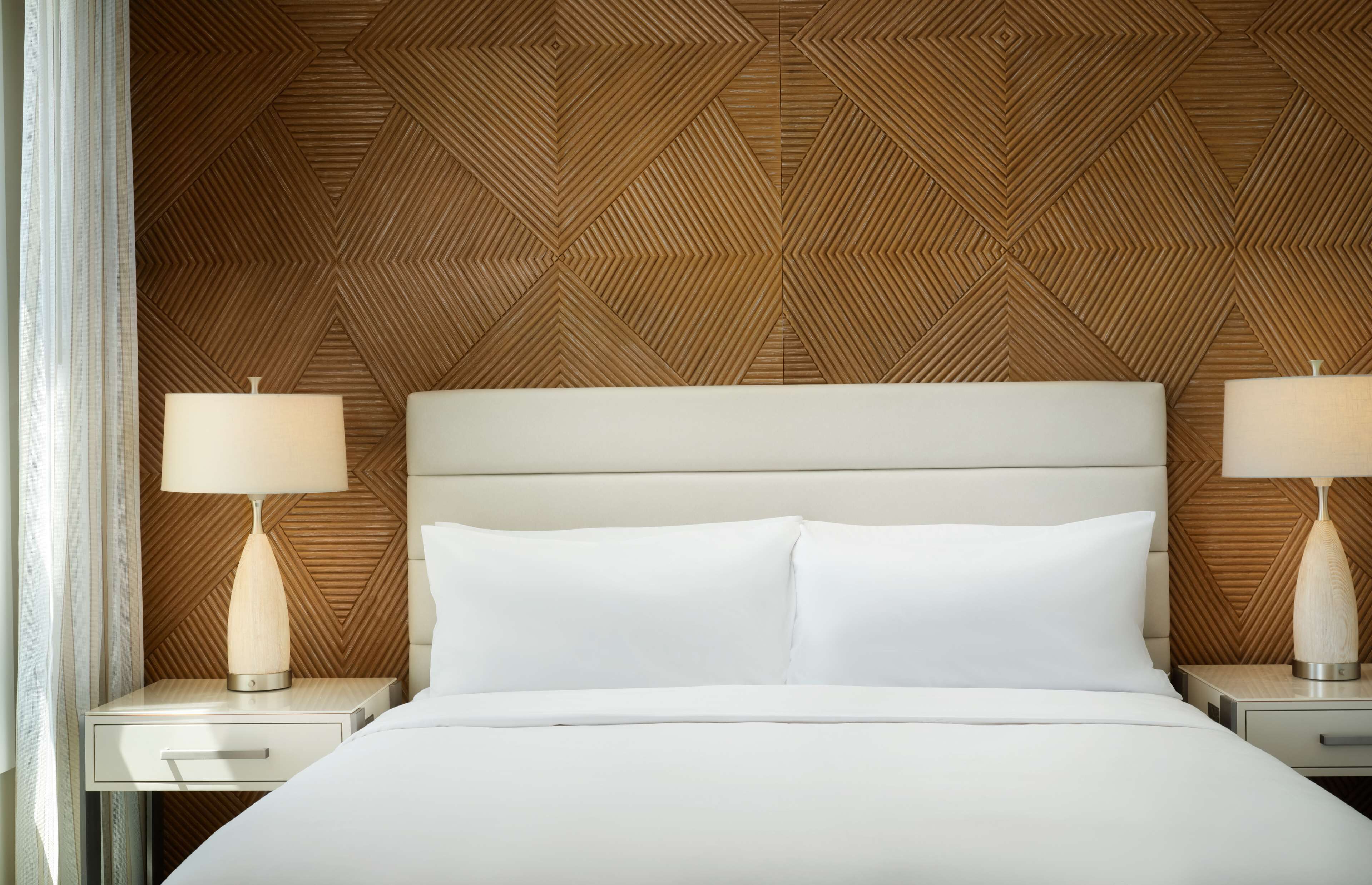 Une chambre d’hôtel avec un lit, deux tables de chevet et des lampes.
