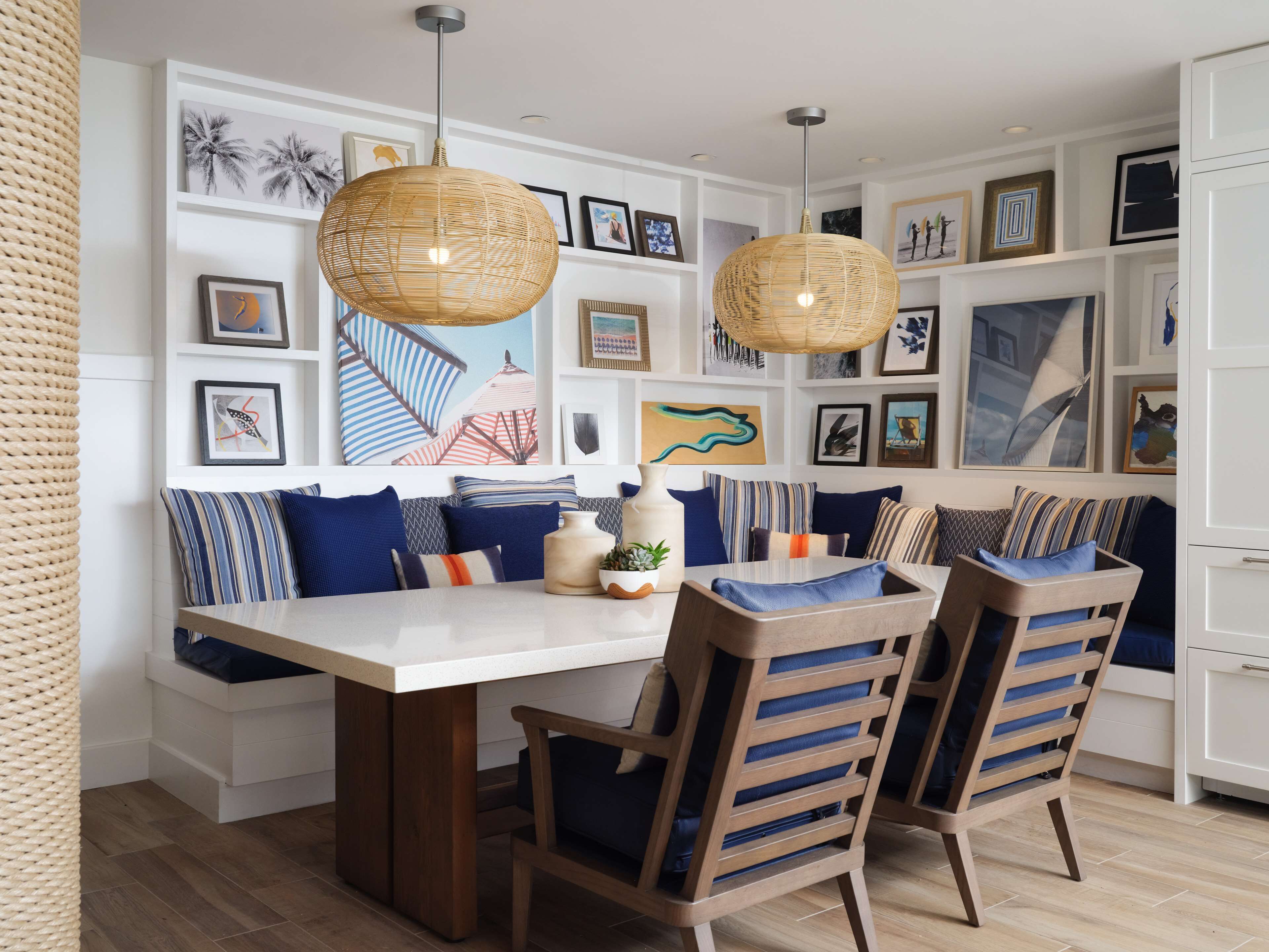 A dining area with a white table, two wooden chairs, and a bench with blue cushions.