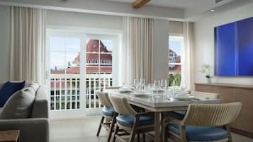 A dining area with a table set for six, large windows, and a view of a building with a red roof.