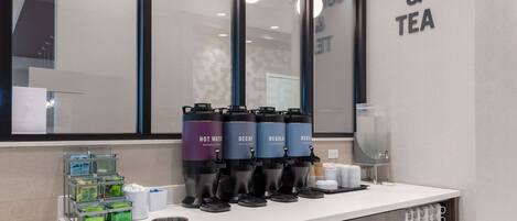 Una estación de café y té con dispensadores etiquetados 'HOT WATER', 'DECAF' y 'REGULAR'.