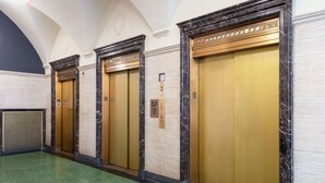 A hallway with four elevators, each with a marble frame and a gold door. - Home2 Suites by Hilton St. Louis Downtown (St. Louis)