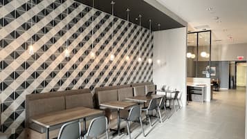 Un restaurant moderne avec des murs aux motifs géométriques, un long comptoir avec des sièges et des luminaires suspendus.