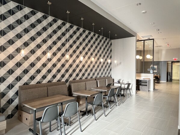 A modern restaurant with geometric patterned walls, a long counter with seating, and pendant lighting. - Tru By Hilton St. Louis Downtown (St. Louis)