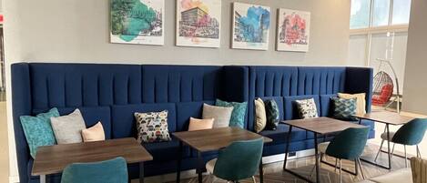 Ein stilvoller Lounge-Bereich mit einem blau bezogenen Sofa, Holztischen und Sitzgelegenheiten in Türkis.