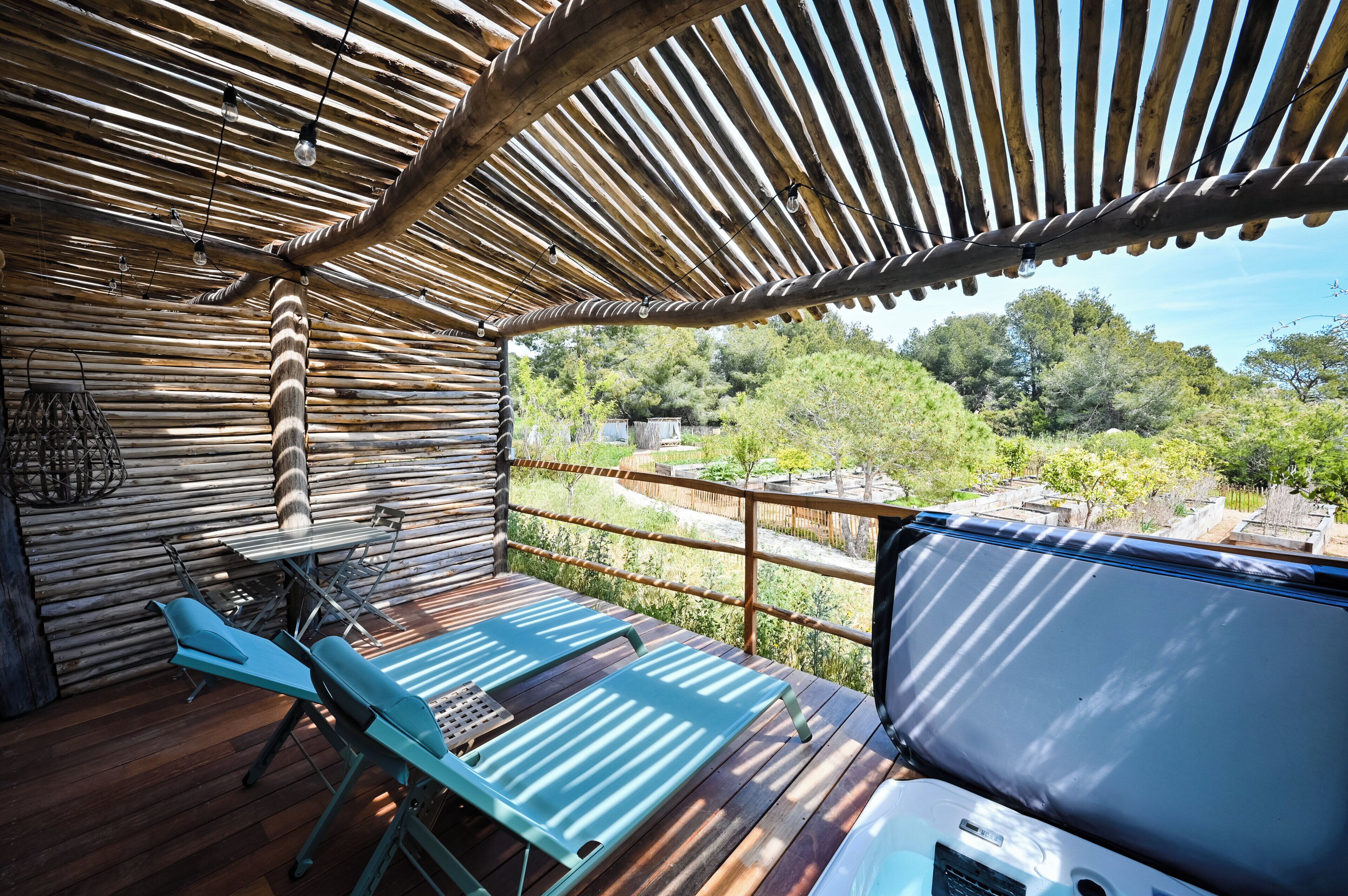 A wooden deck with a table and chairs, a ceiling with wooden beams, and a view of trees and buildings.