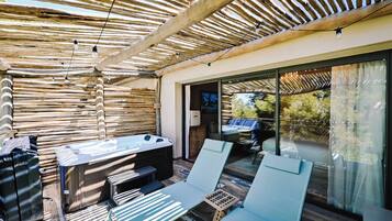 Un patio exterior con un jacuzzi, sillones de descanso y una pérgola de madera.