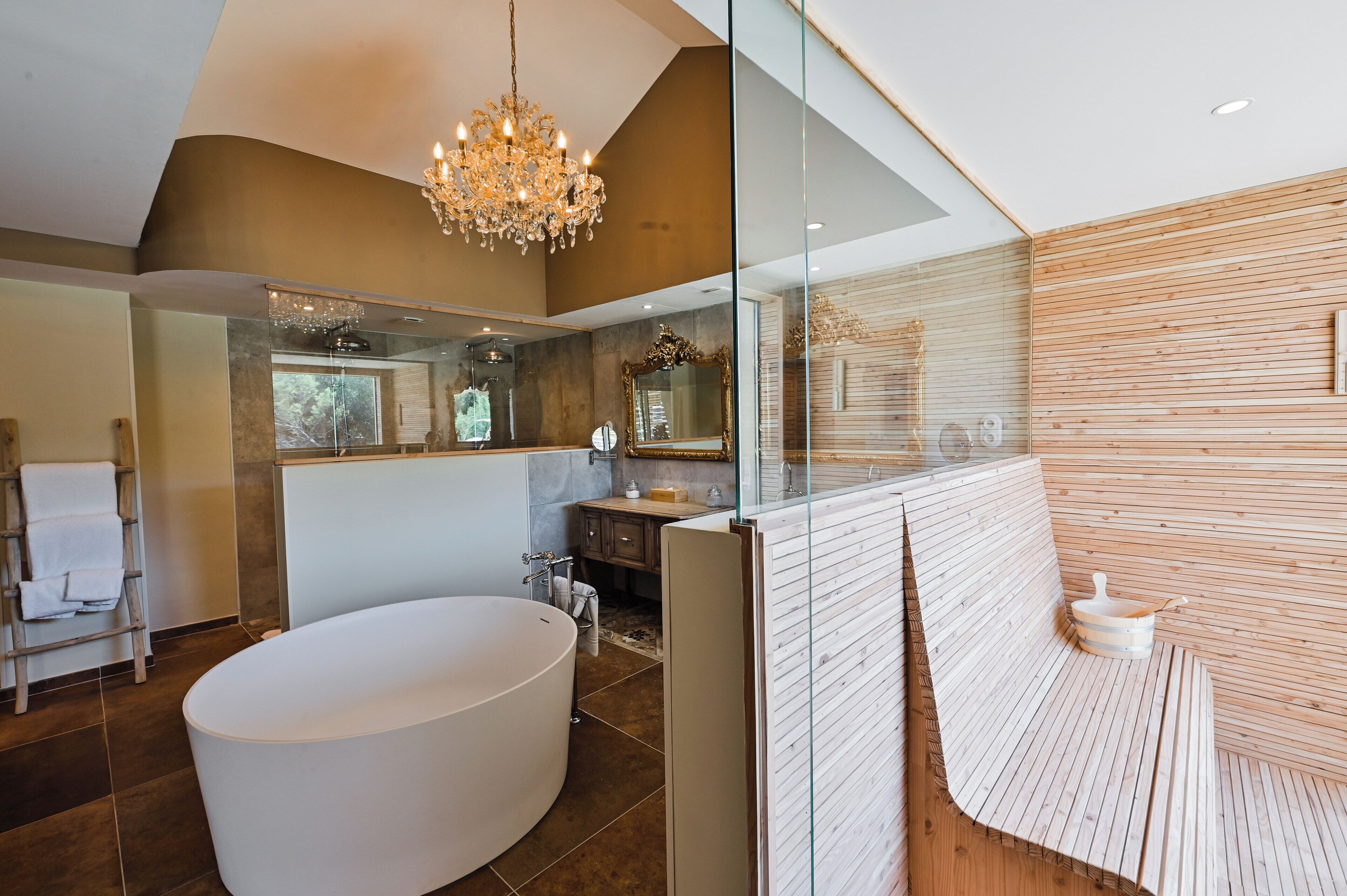 Een moderne badkamer met een vrijstaand bad, een glazen douchecabine en een houten bankje.