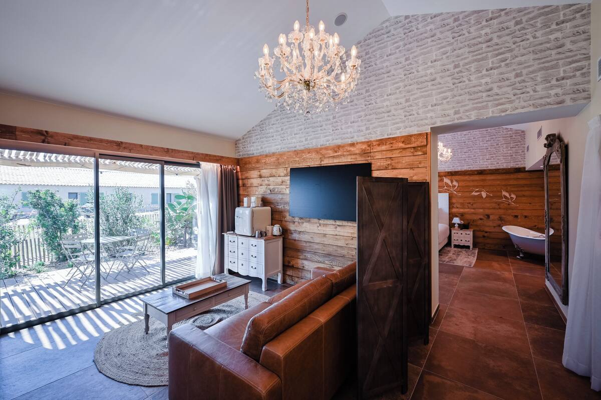A modern living room with a large window, a chandelier, and a wooden wall.
