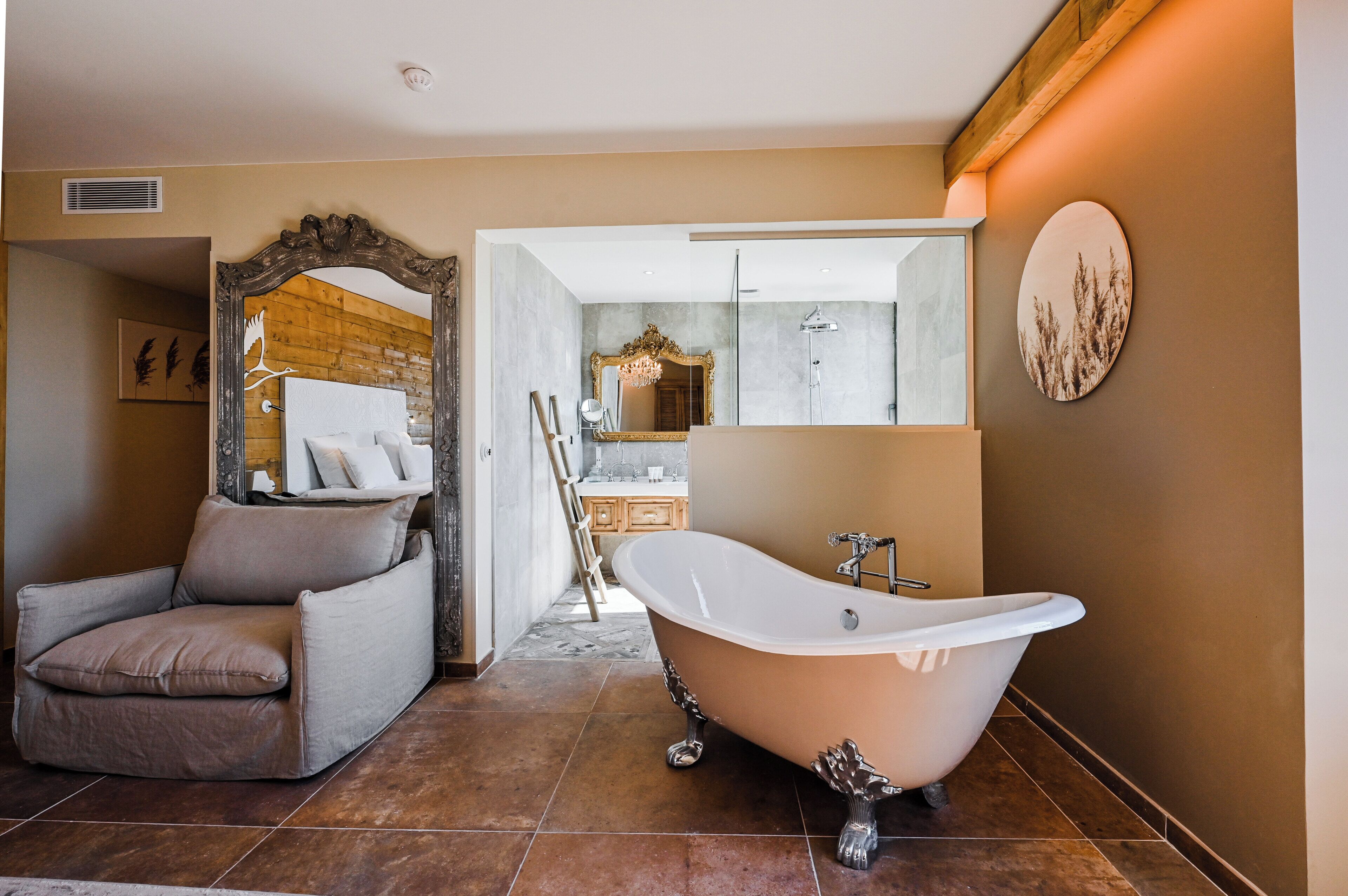 Un baño con una bañera de patas de león, una silla de madera y un espejo con un marco ornamentado.
