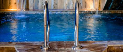 Ein Whirlpool mit Holzwand im Hintergrund und einer gefliesten Plattform.