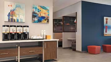 Eine moderne Hotelhalle mit einer Kaffeestation, Kunstwerken an den Wänden und Sitzbereichen.