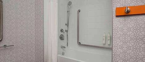 A bathroom with a shower, grab bars, and a towel rack.