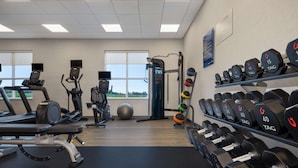 A gym with treadmills, an elliptical, a weight bench, and a rack of dumbbells. - Hampton Inn by Hilton Port Hope Cobourg (Port Hope)