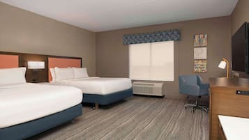 A hotel room with two beds, a desk, a chair, a TV, and a window with a view.
