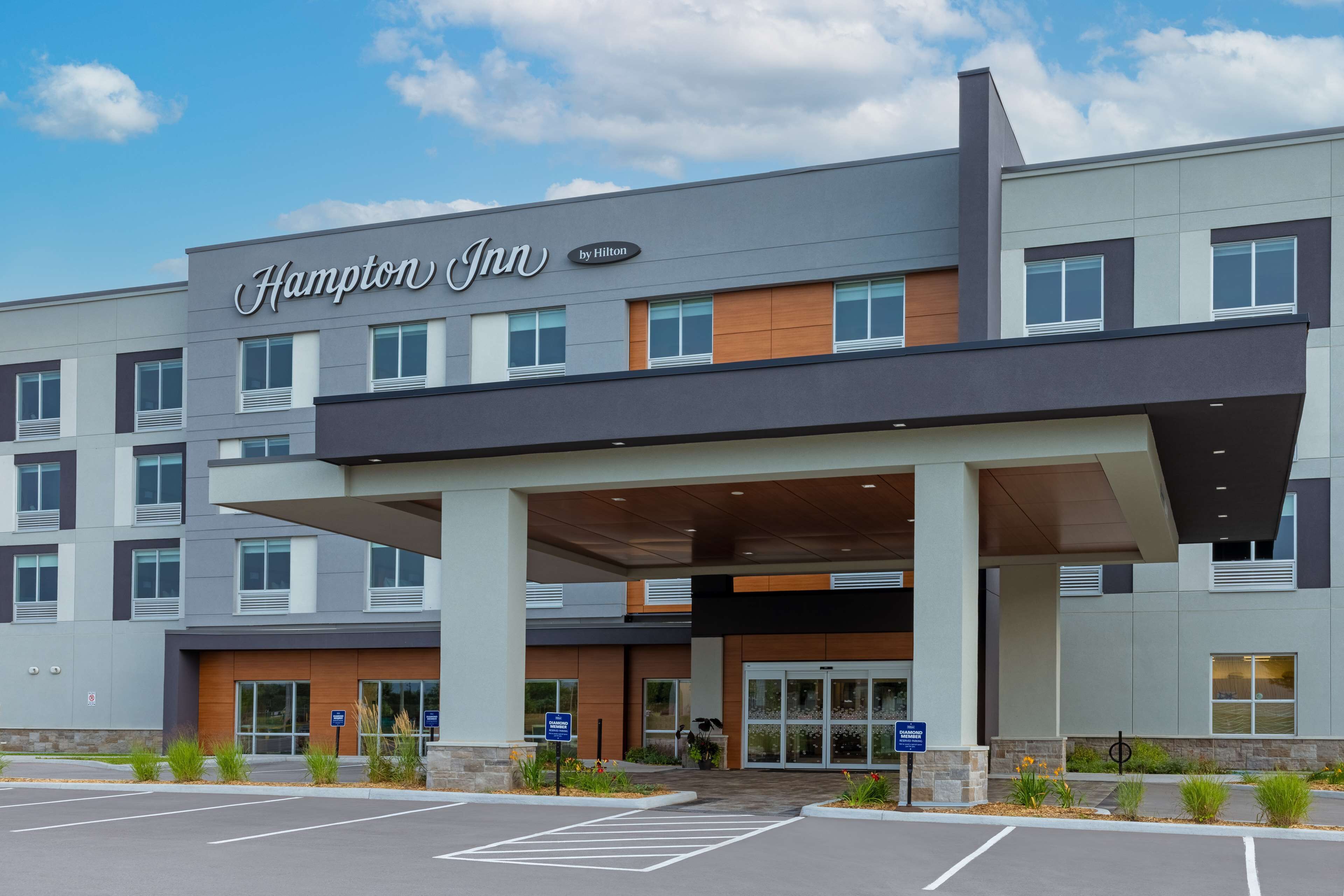 A Hampton Inn hotel with a modern facade, large entrance, and a parking lot.