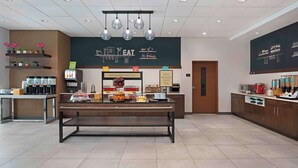 A breakfast area with a buffet setup, coffee machines, and a chalkboard menu. - Hampton Inn by Hilton Port Hope Cobourg (Port Hope)