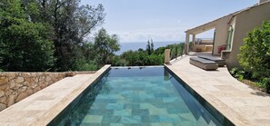 A rectangular infinity pool with clear water, surrounded by stone walls and lush greenery.