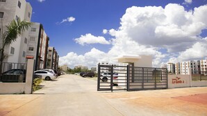 Een omheind wooncomplex met meerdere gebouwen, een heldere lucht en geparkeerde auto's.