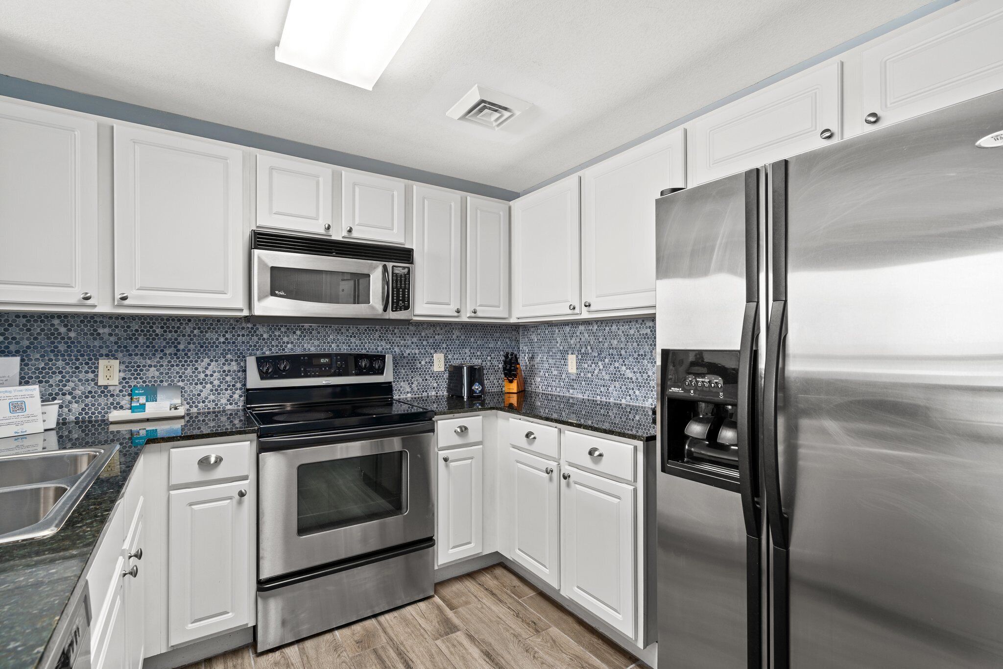 Uma cozinha moderna com armários brancos, eletrodomésticos de aço inoxidável e backsplash revestido de azulejos azuis.