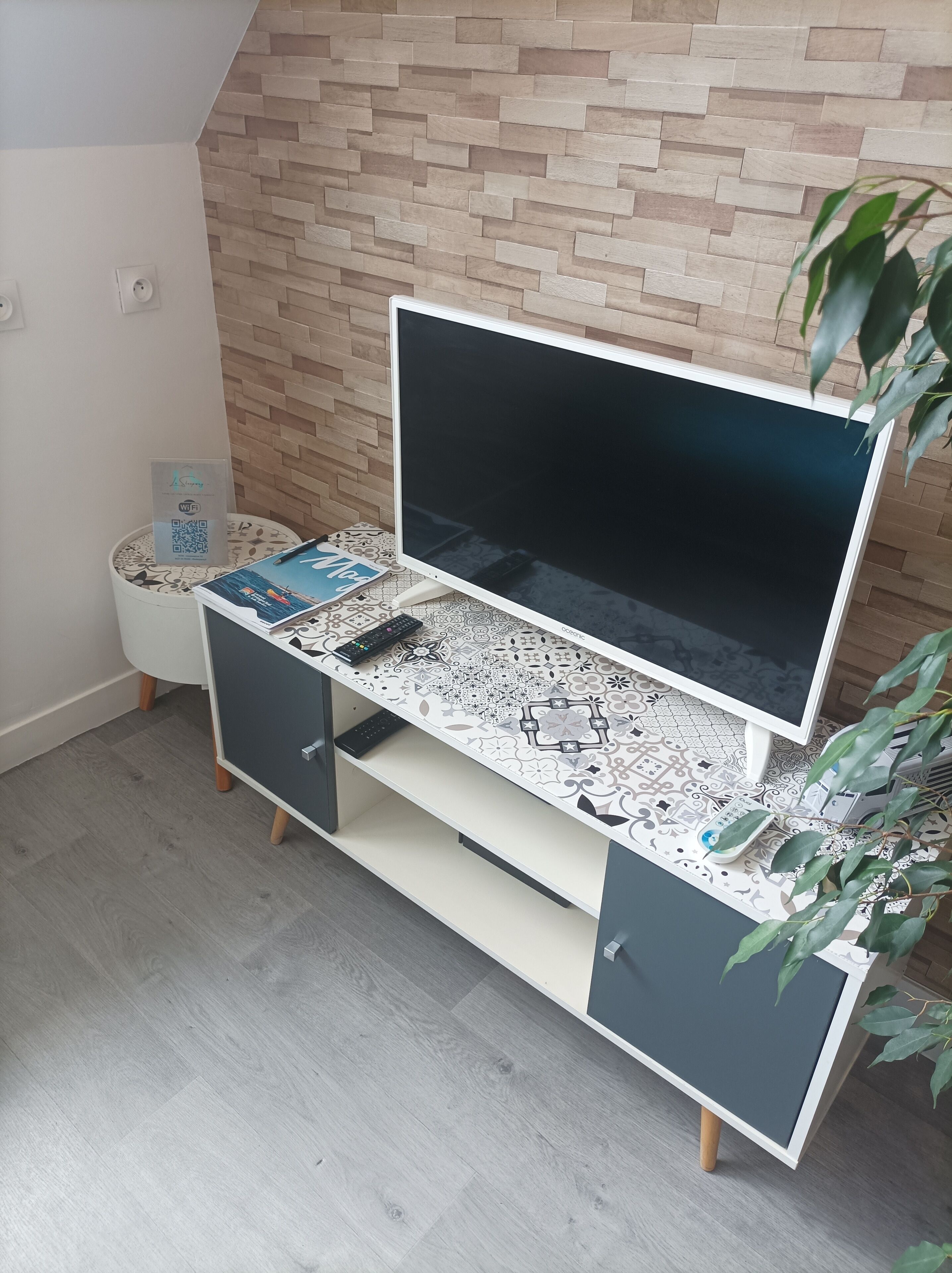 A modern entertainment unit with a flat-screen TV, a remote control, and a decorative tray.