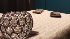 Een kamer met een bed, een decoratieve kristallen bol, een ingelijst plaatje aan de muur en een donker gordijn.