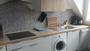 Een moderne keuken met een wasmachine, een koffiezetapparaat en een betegelde spatwand.