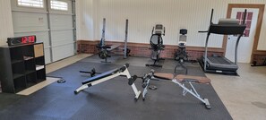 A gym with various exercise equipment, a digital clock, and a door in the background.