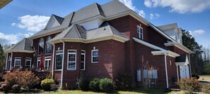 A large brick house with a gabled roof, multiple windows, and a covered front porch.