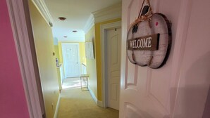 Un pasillo con un cartel de 'WELCOME', una puerta y un banco.