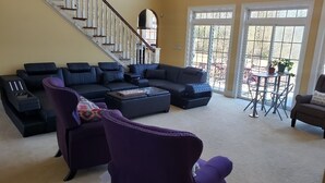 Una sala de estar con un sofá modular, un sillón morado y una mesa de centro.