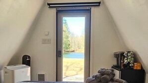 Un dormitori amb llit, un calefactor, una finestra amb vista a un llac i una porta.