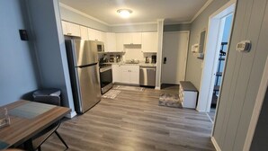 Una cocina moderna con electrodomésticos de acero inoxidable, armarios blancos y piso de madera.