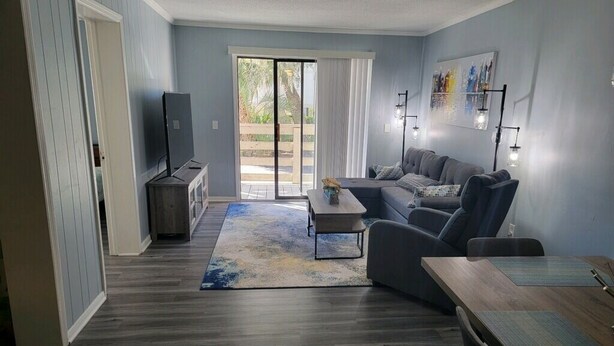 Una sala de estar moderna con un sofá gris, una mesa de centro de madera y un mueble para televisor.