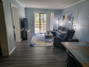 Una sala de estar moderna con un sofá gris, una mesa de centro de madera y un mueble para televisor.