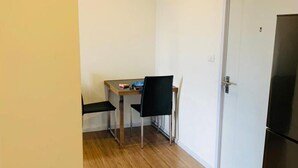 A small, compact kitchen with a dining area, wooden flooring, and a white door. - Lovely 2-bed Apart - 19th Floor Notting Hill Bldg (Samut Prakan)