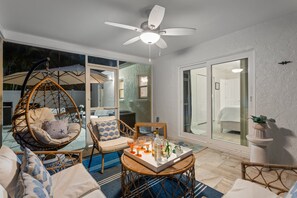 A cozy outdoor seating area with wicker furniture, a ceiling fan, and a tray with drinks and snacks.