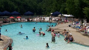 Una piscina pública con múltiples carriles, rodeada de sombrillas y sillas de descanso.